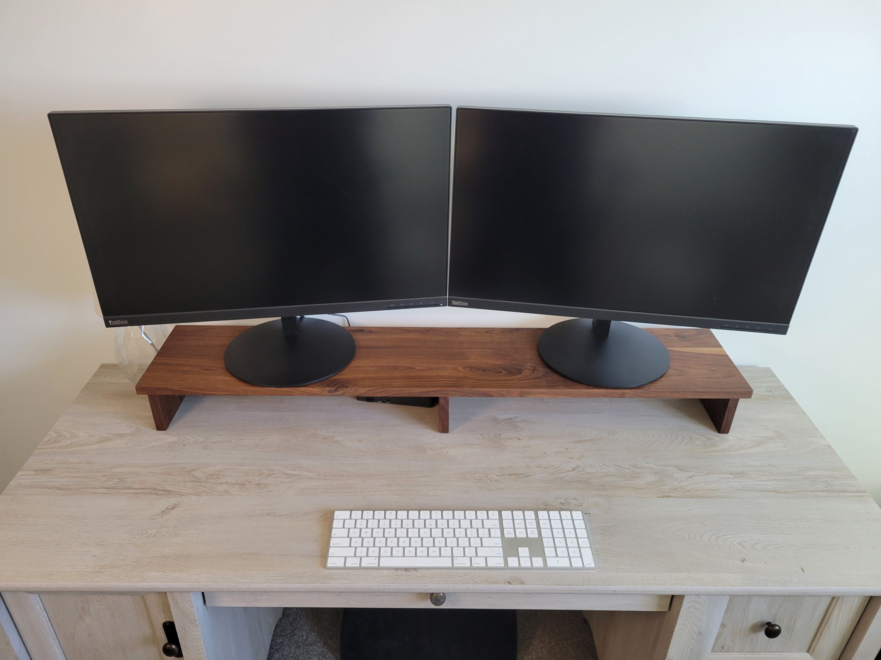 two computer monitors sitting on top of a 45: monitor riser